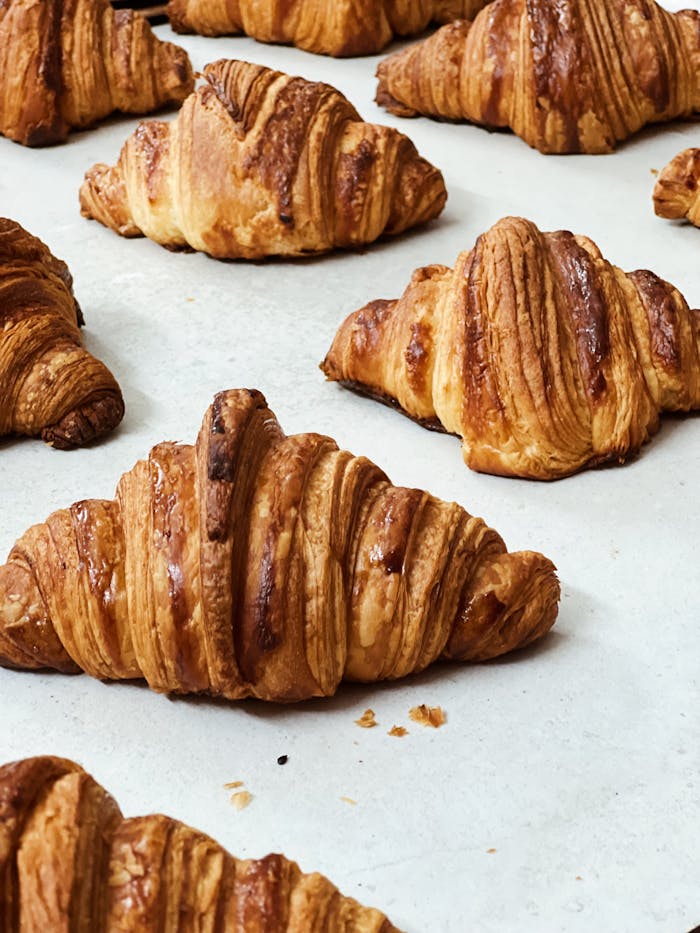 Delicious freshly baked croissants with crispy layers on a baking sheet.