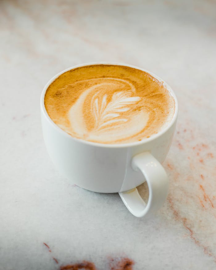 A beautifully crafted cappuccino with latte art served on a marble table.