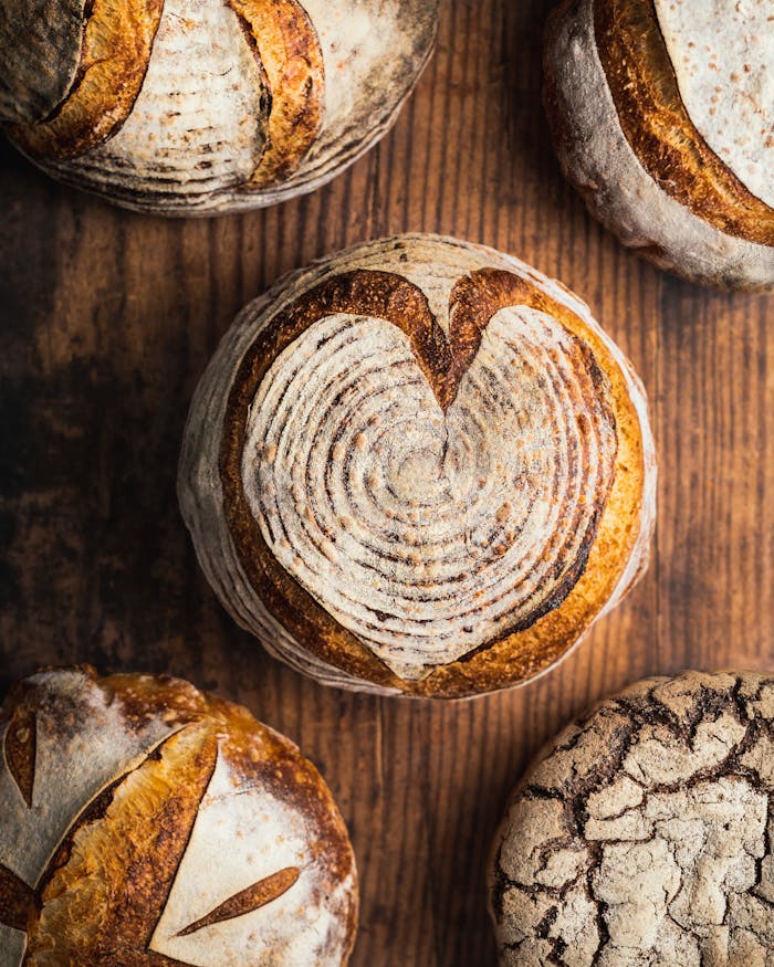 Top view of various artisan bread loaves with intricate designs, perfect for bakery promotions.