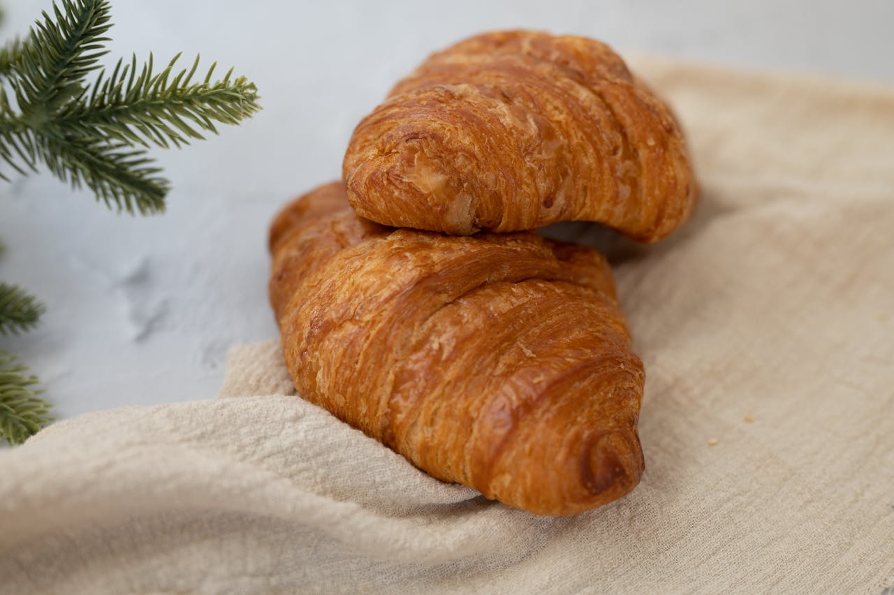 Fresh, buttery croissants on a linen cloth, styled for elegant breakfast photography.